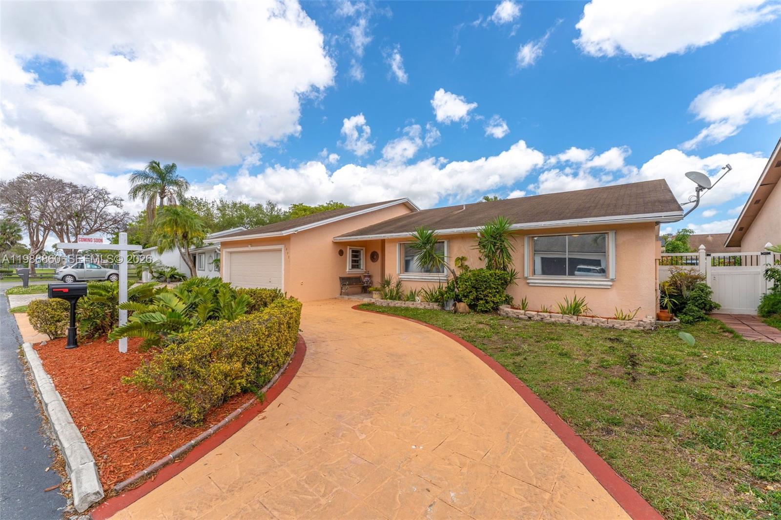 A single-story peach-colored house features a curved driveway, a garage, and a front lawn — 10021 SW 145th Pl, Miami FL 33186, MIAMI, FL