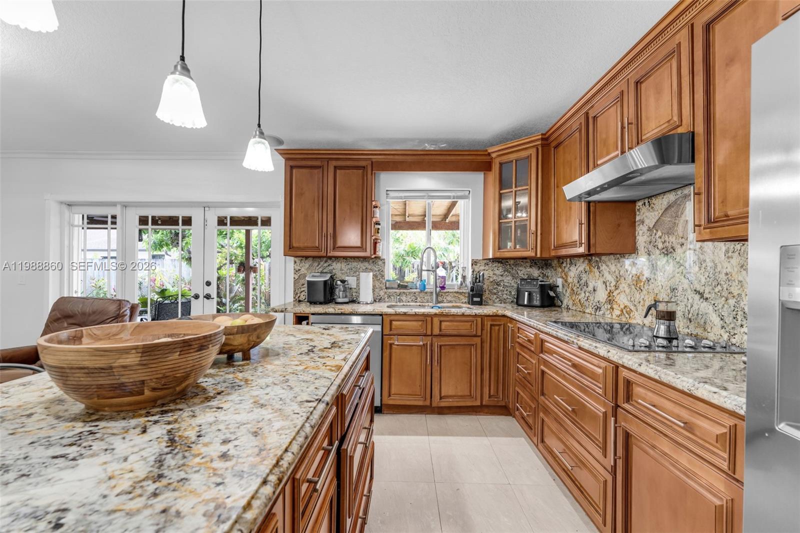 A kitchen features wood cabinets, granite countertops, a stainless steel range hood, and pendant lighting — 10021 SW 145th Pl, Miami FL 33186, MIAMI, FL