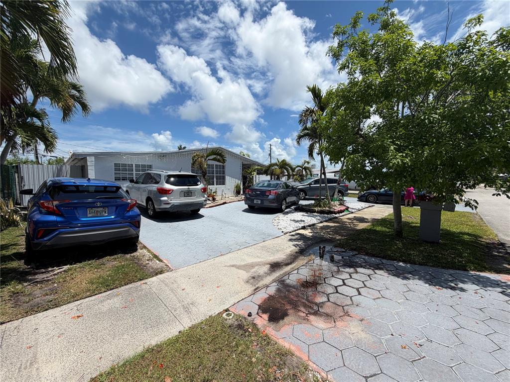 A single-story house with a paved driveway featuring several parked cars under a blue sky — 18615 SW 98TH AVENUE, MIAMI, FL