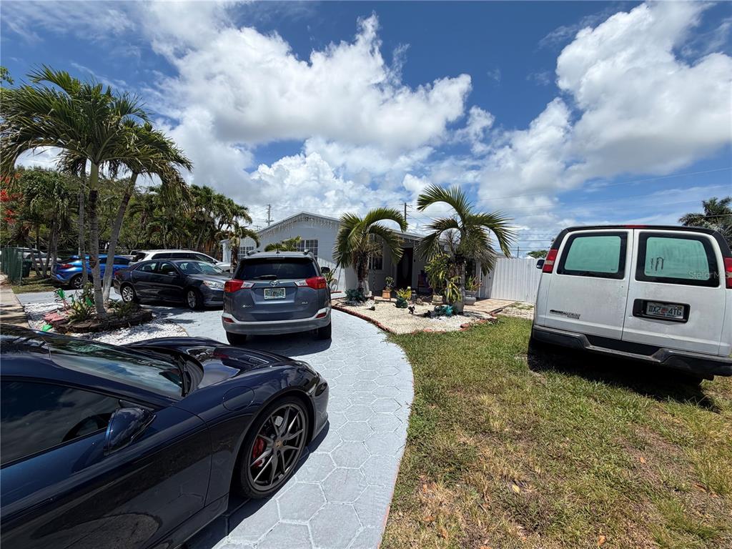 A driveway with multiple parked vehicles leads to a single-story house with palm trees — 18615 SW 98TH AVENUE, MIAMI, FL