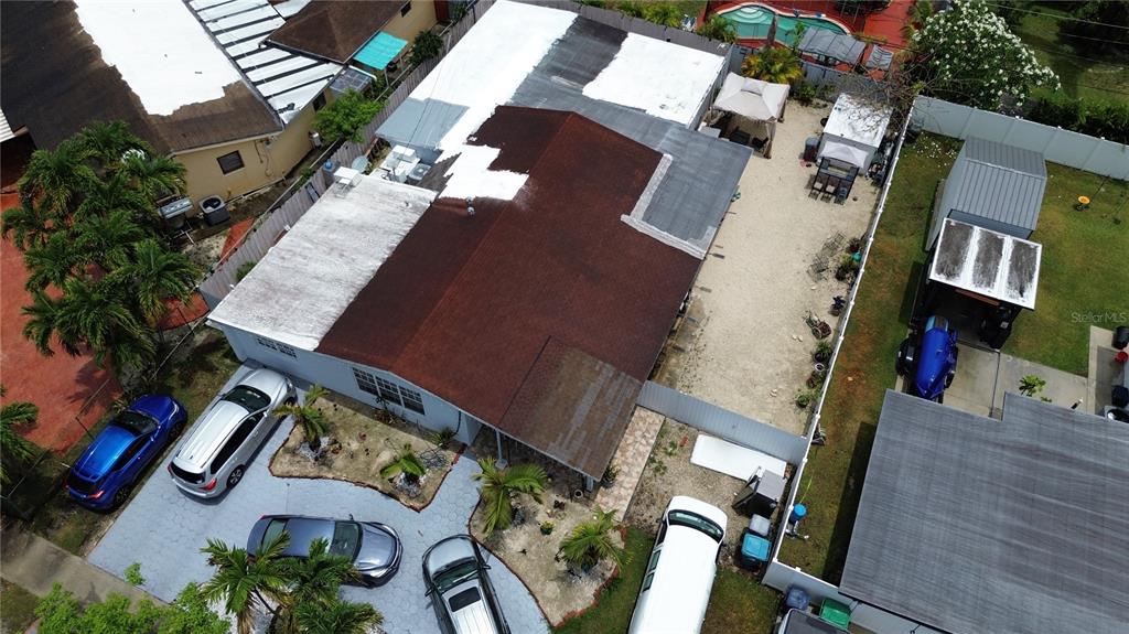 An aerial view shows a house with a partially white-coated roof and several parked cars — 18615 SW 98TH AVENUE, MIAMI, FL