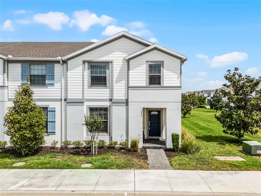 A two-story townhouse exterior features white horizontal siding, gray trim, and a dark front door — 2427 DUBAI STREET, KISSIMMEE, FL