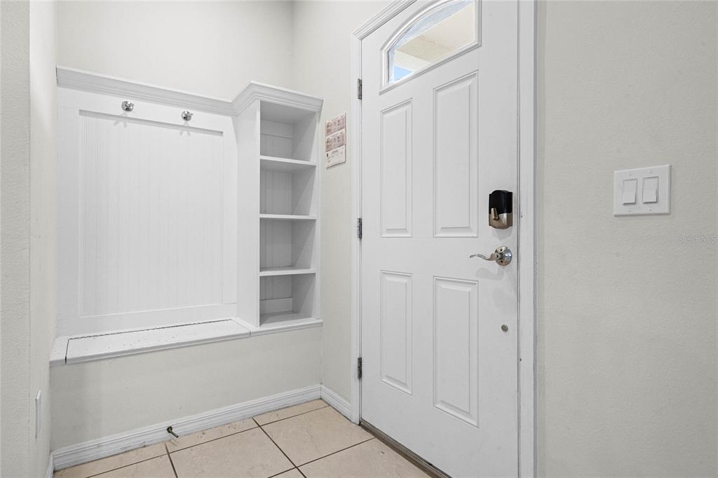 An entryway features a white built-in bench with shelving, a white door, and tiled flooring — 2427 DUBAI STREET, KISSIMMEE, FL