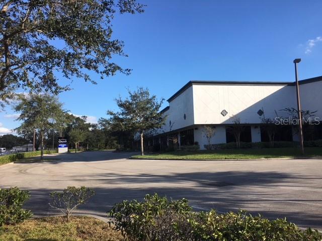 A large white commercial building sits behind a paved parking lot with surrounding trees — 6859 EDGEWATER COMMERCE PARKWAY, ORLANDO, FL