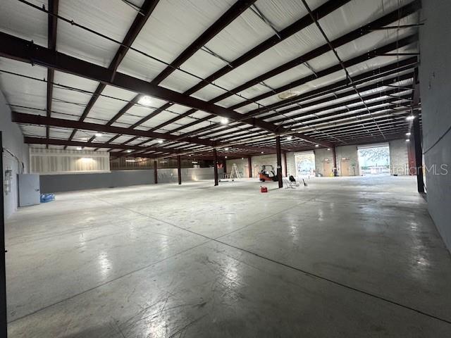 A large, open warehouse space features a concrete floor and exposed steel ceiling beams — 6859 EDGEWATER COMMERCE PARKWAY, ORLANDO, FL