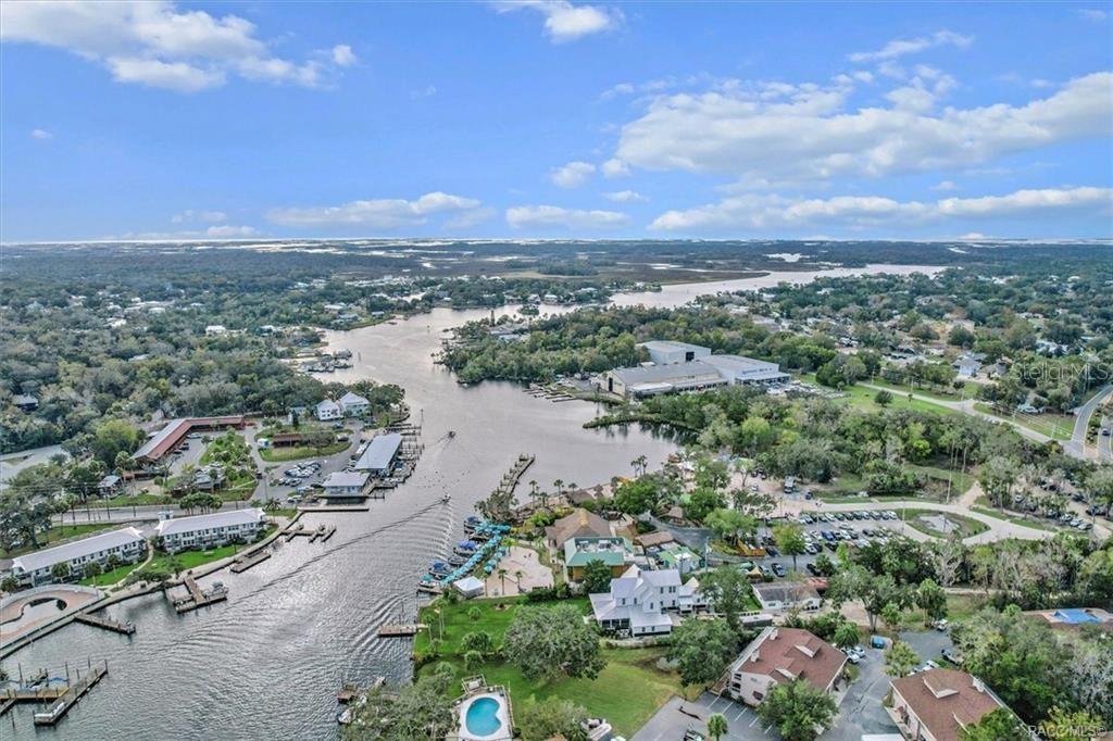 An aerial view shows a river winding through a coastal area with docks and buildings — 10460 W NEW YORK STREET, HOMOSASSA, FL