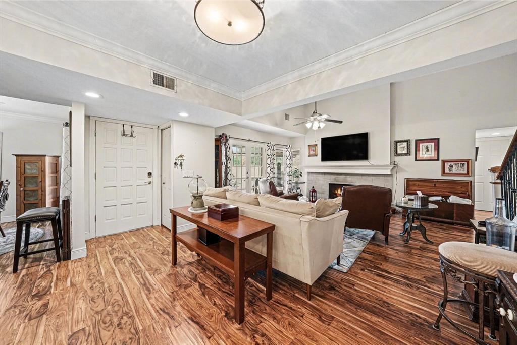 A living room features wood-look flooring, a fireplace with a mounted television, and a sofa — 4805 UMBER COURT, TAMPA, FL