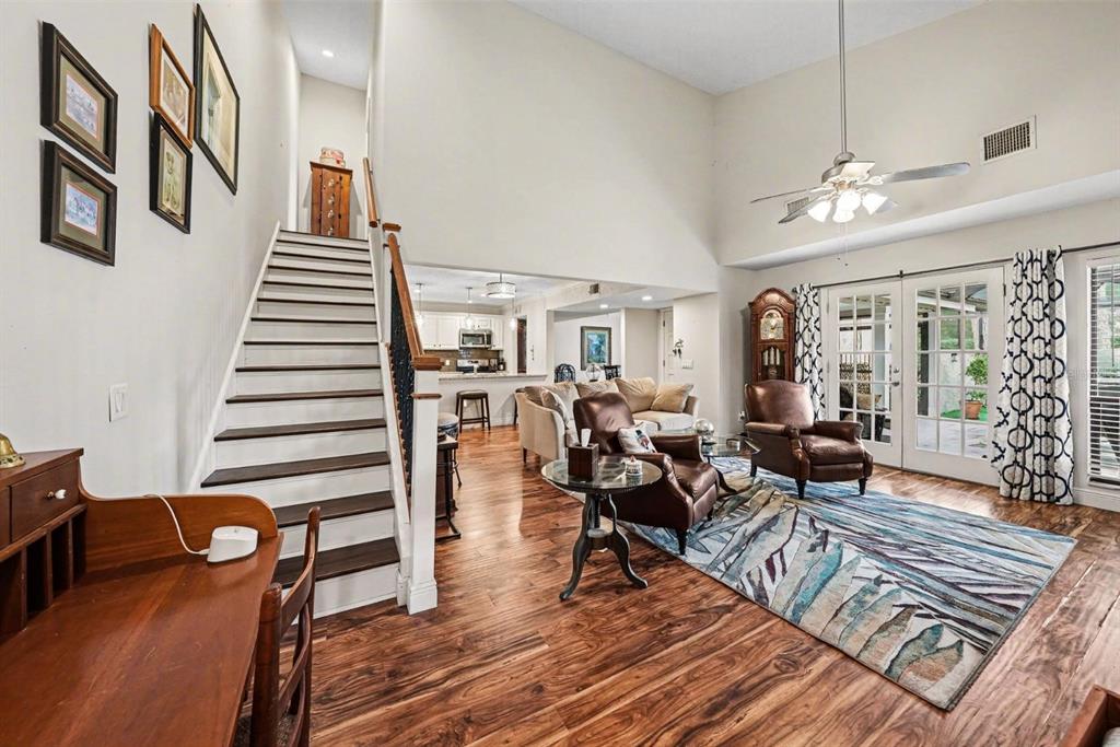 A living room with hardwood floors, a staircase, and a view into the kitchen — 4805 UMBER COURT, TAMPA, FL
