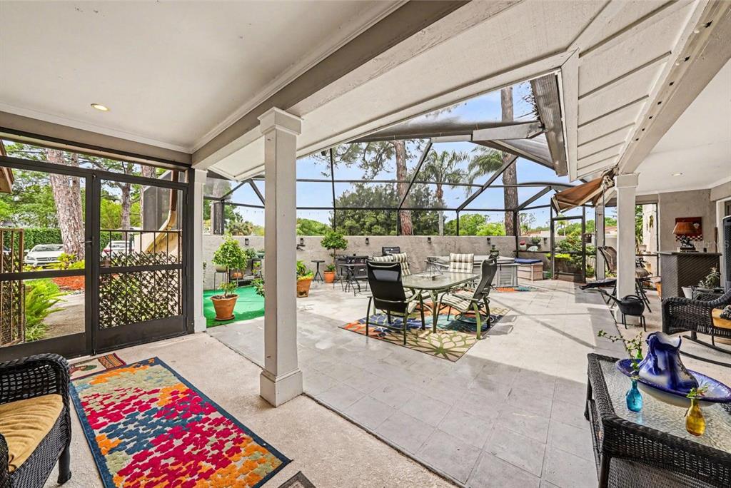 A covered, screened-in patio features tiled flooring, outdoor furniture, and a view of the backyard — 4805 UMBER COURT, TAMPA, FL