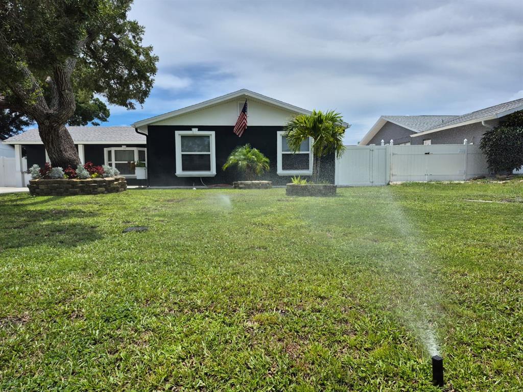 A single-story house with black exterior walls and a white trim sits behind a lawn — 5817 TAMPA SHORES BOULEVARD, TAMPA, FL