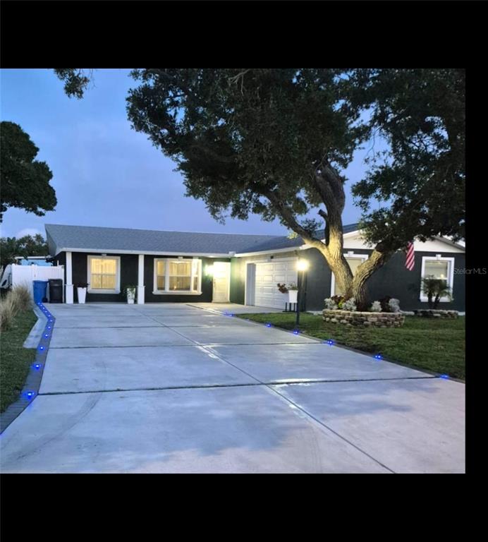 A dark-painted single-story house with a concrete driveway lined with blue solar lights — 5817 TAMPA SHORES BOULEVARD, TAMPA, FL