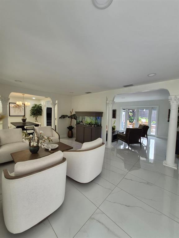 A living room with white tile floors, white armchairs, and a large fish tank — 5817 TAMPA SHORES BOULEVARD, TAMPA, FL