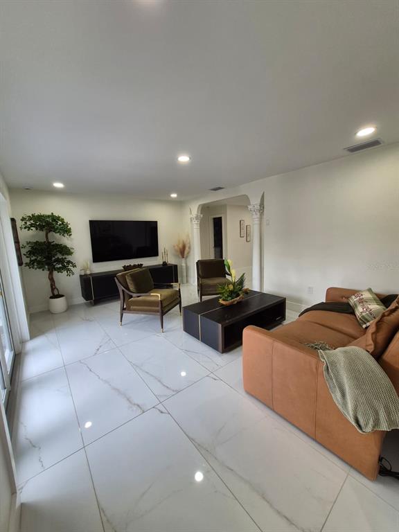 A living room features white marble-look tile flooring, a brown leather sofa, and two armchairs — 5817 TAMPA SHORES BOULEVARD, TAMPA, FL