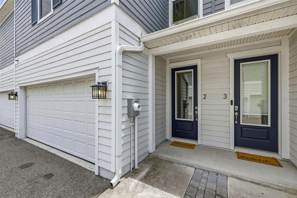 The exterior of a townhouse features a garage, two blue front doors, and light siding — 6621 S MANHATTAN AVENUE UNIT 2, TAMPA, FL