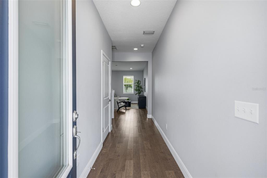 A narrow hallway with wood-look flooring leads from an entryway toward a living area — 6621 S MANHATTAN AVENUE UNIT 2, TAMPA, FL