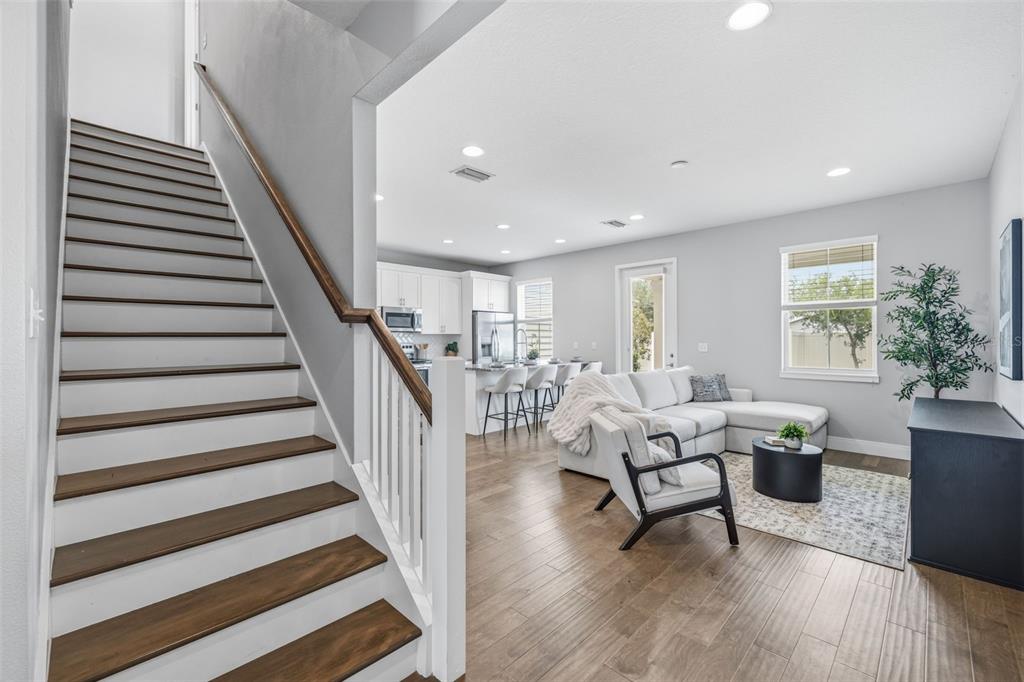 A staircase with wooden treads leads to an open-concept living area with a kitchen — 6621 S MANHATTAN AVENUE UNIT 2, TAMPA, FL