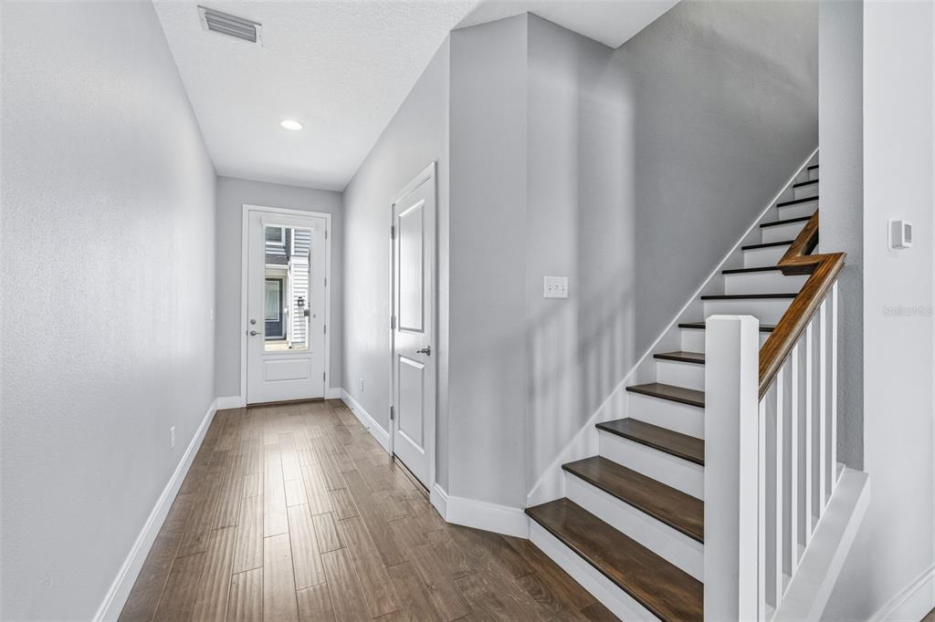 An entryway with wood-look tile flooring, a white front door, and a staircase with wood treads — 6621 S MANHATTAN AVENUE UNIT 2, TAMPA, FL