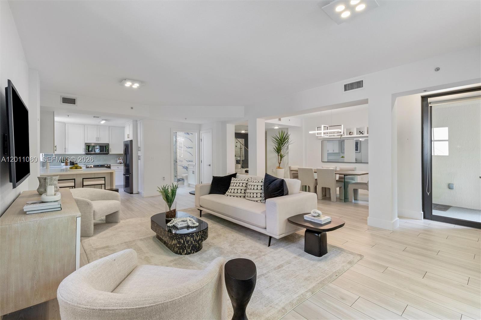 A bright, open-concept living and dining area features light wood-look tile flooring and modern furniture — 1650 Galiano St, Coral Gables FL 33134, CORAL GABLES, FL