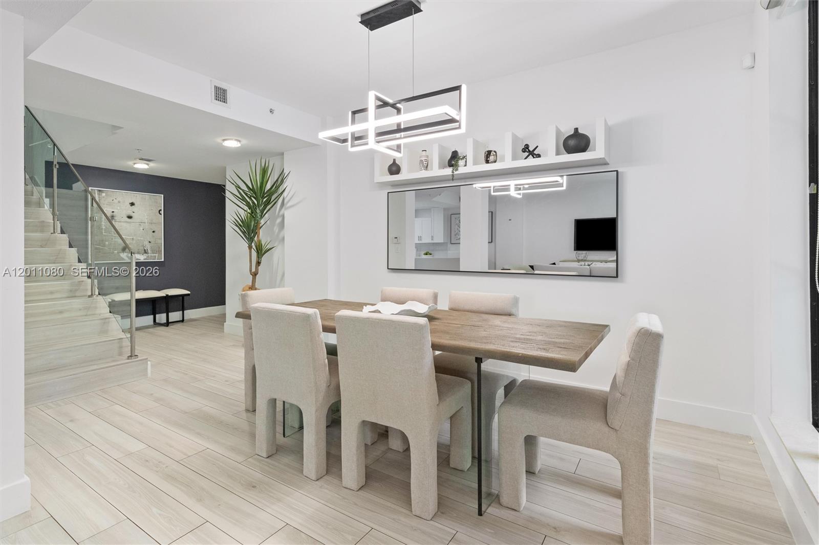 A dining room features a wooden table, upholstered chairs, a modern chandelier, and a mirror — 1650 Galiano St, Coral Gables FL 33134, CORAL GABLES, FL
