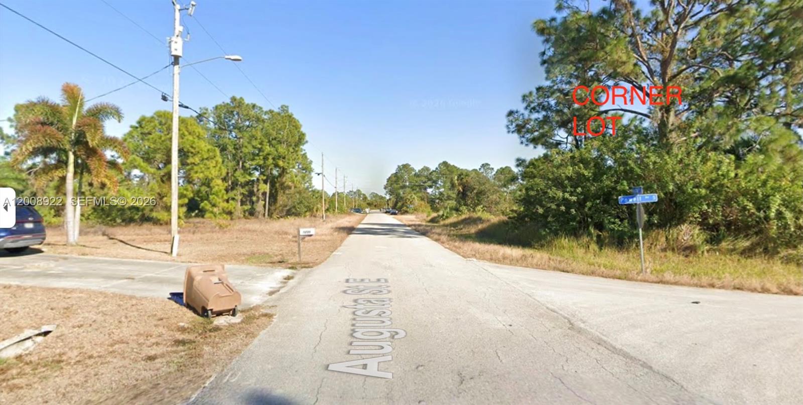 A paved road intersects with a side street at a vacant, tree-lined corner lot — 507 POWELL AVE S, Lehigh Acres FL 33974, LEHIGH ACRES, FL