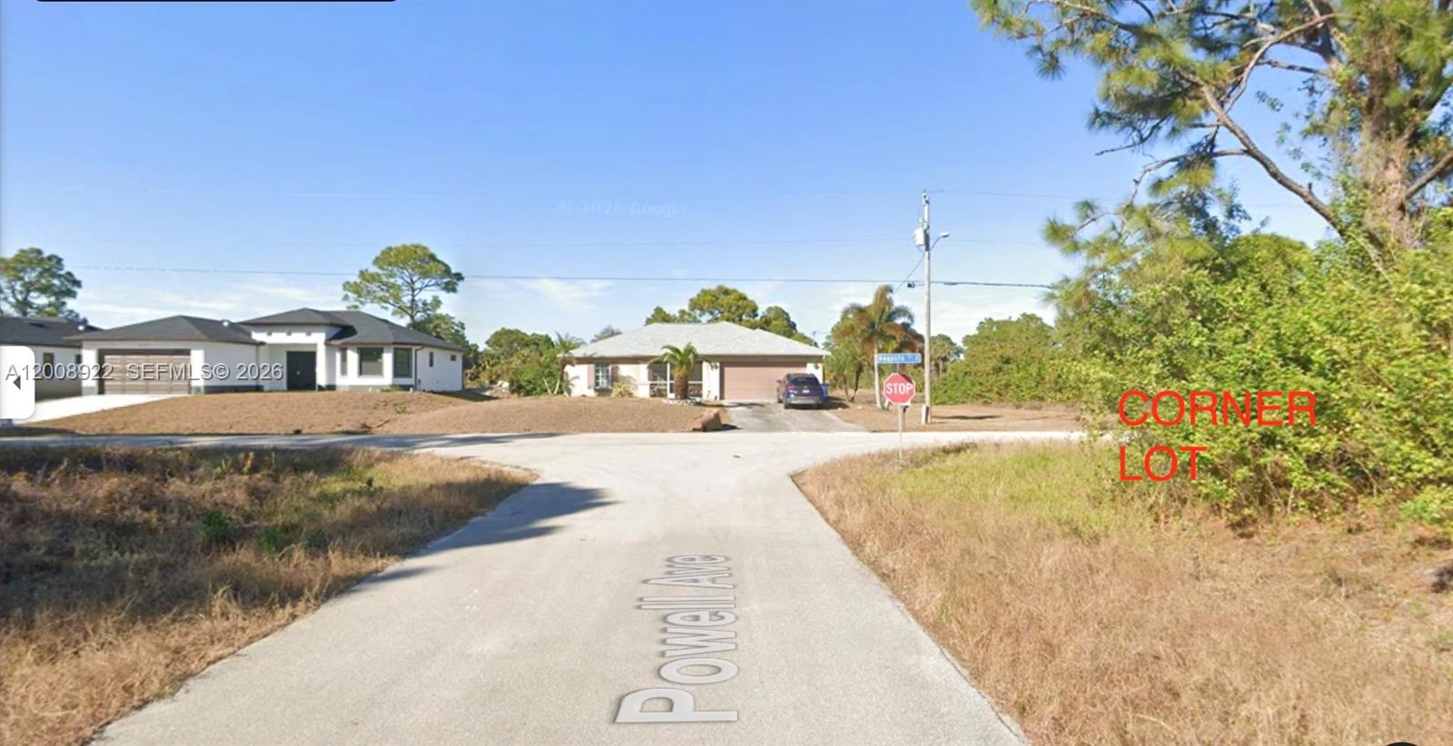 A paved road leads to a T-intersection with a stop sign and nearby houses — 507 POWELL AVE S, Lehigh Acres FL 33974, LEHIGH ACRES, FL