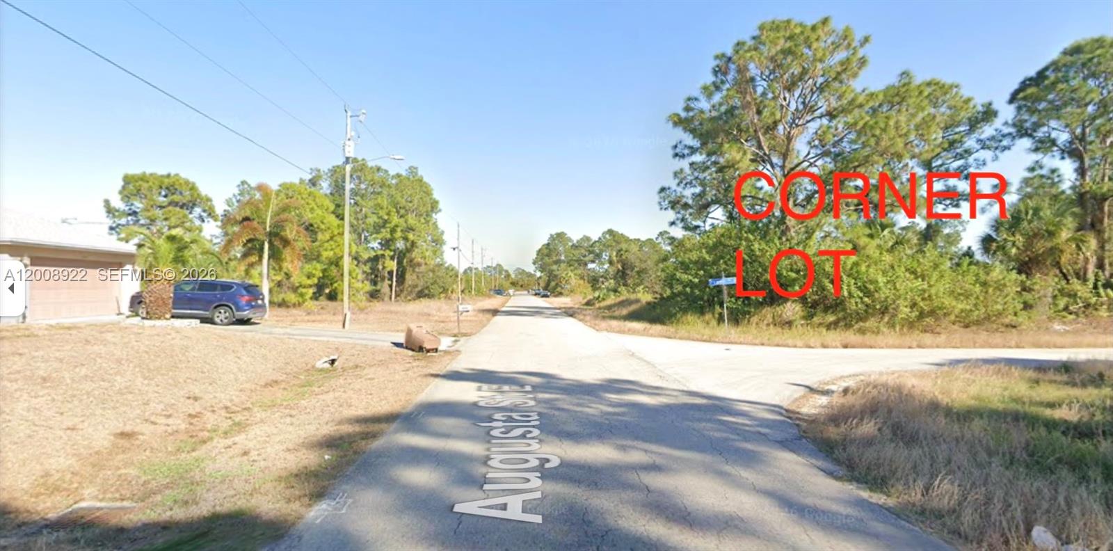 This street-level view shows a paved road intersection with a vacant corner lot — 507 POWELL AVE S, Lehigh Acres FL 33974, LEHIGH ACRES, FL