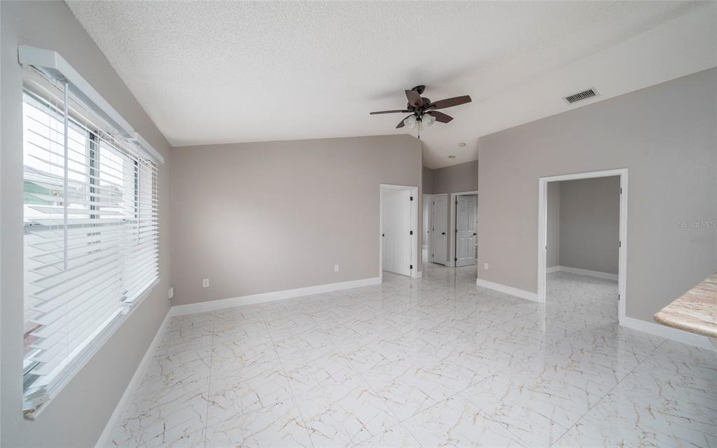 A bright room with white marble-patterned tile flooring, a ceiling fan, and multiple doorways — 10201 VISTA COVE LANE, ORLANDO, FL