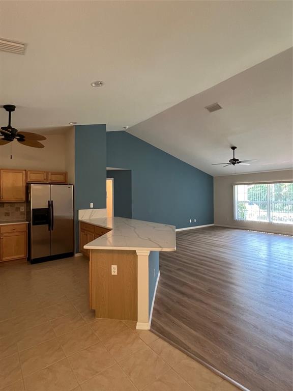 A kitchen with wood cabinets and a quartz island opens into a large living area — 2634 TWINKLE AVENUE, NORTH PORT, FL