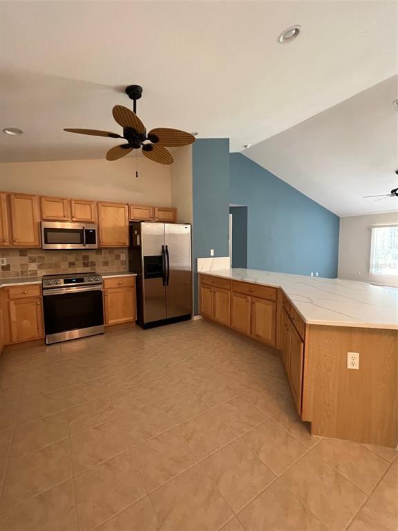 A kitchen features light wood cabinets, stainless steel appliances, and a large angled island — 2634 TWINKLE AVENUE, NORTH PORT, FL