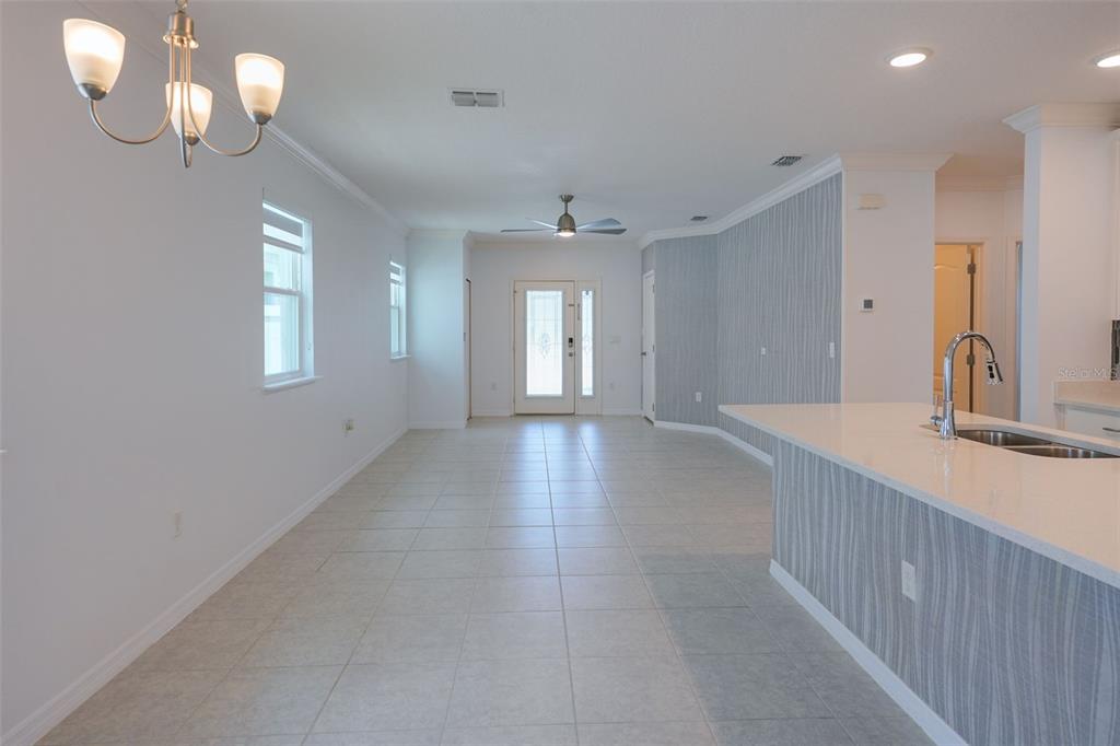 A bright, open-concept room features light tile flooring, a kitchen island, and a front entryway — 173 VILLAVISTA COURT, DAVENPORT, FL