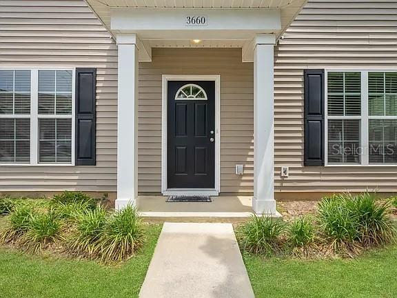 The front exterior of a house features a black door, white columns, and beige siding — 3660 TYSON GREEN WAY UNIT 707, TALLAHASSEE, FL