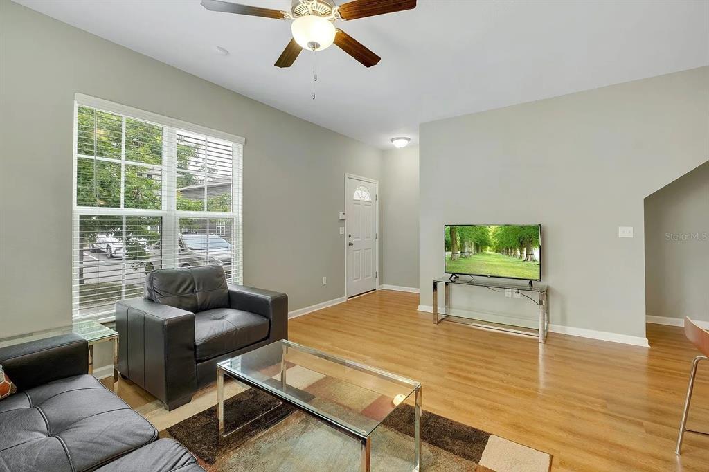 A living room features light-colored walls, hardwood floors, a ceiling fan, and a glass coffee table — 3660 TYSON GREEN WAY UNIT 707, TALLAHASSEE, FL