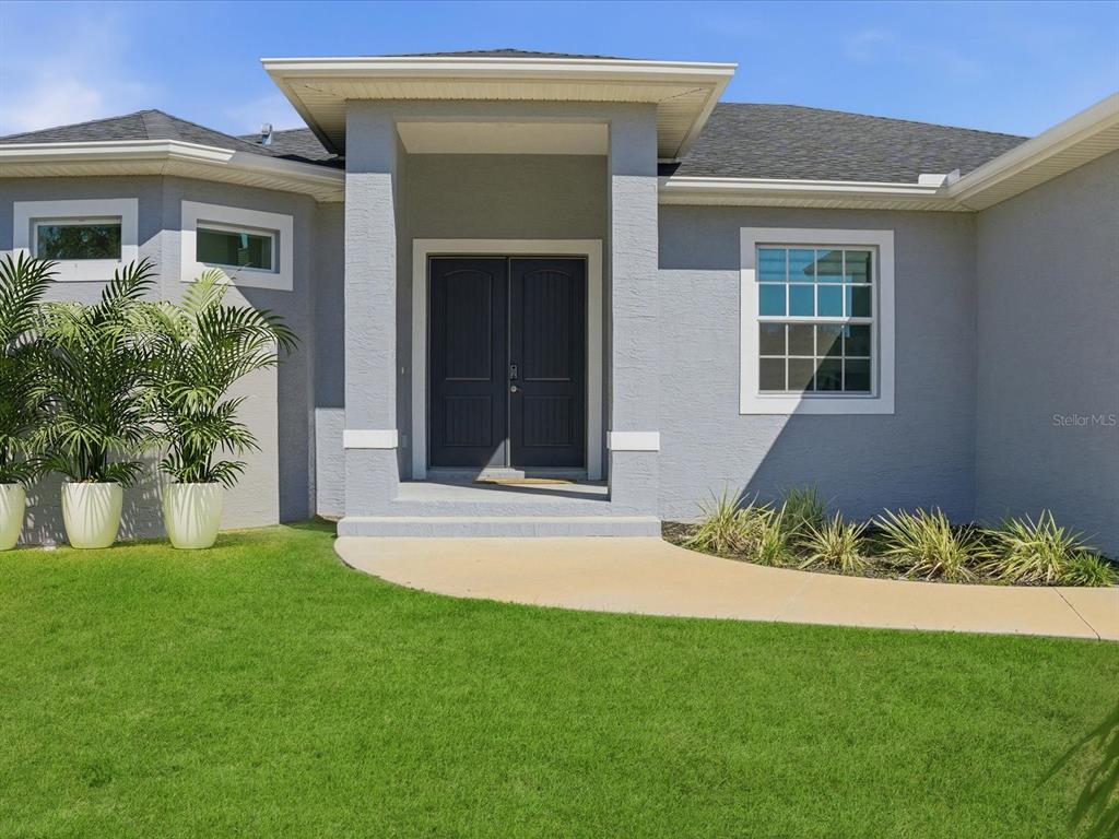 A gray house exterior features a double front door under a covered entryway — 17 PINE VALLEY LANE, ROTONDA WEST, FL
