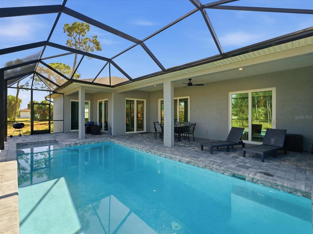 A swimming pool sits on a paved patio enclosed by a screened-in lanai — 17 PINE VALLEY LANE, ROTONDA WEST, FL