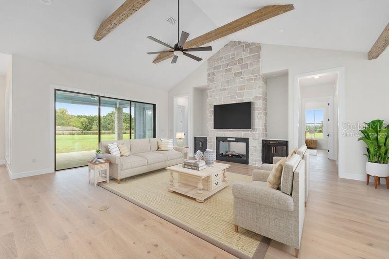 A living room features a stone fireplace, vaulted ceilings with wood beams, and large sliding doors — 11324 NW 50 LANE, OCALA, FL
