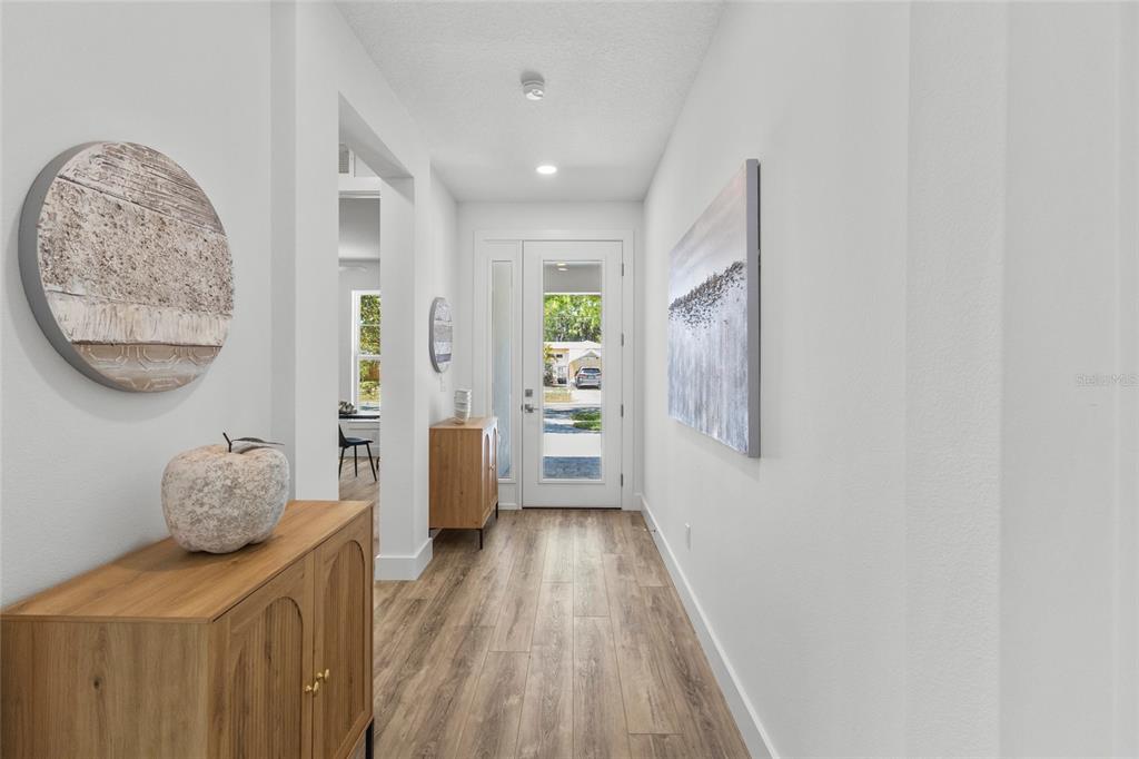 A bright entryway features wood-look flooring, white walls, a glass-paneled front door, and wooden cabinets — 217 S SHADE AVENUE, SARASOTA, FL
