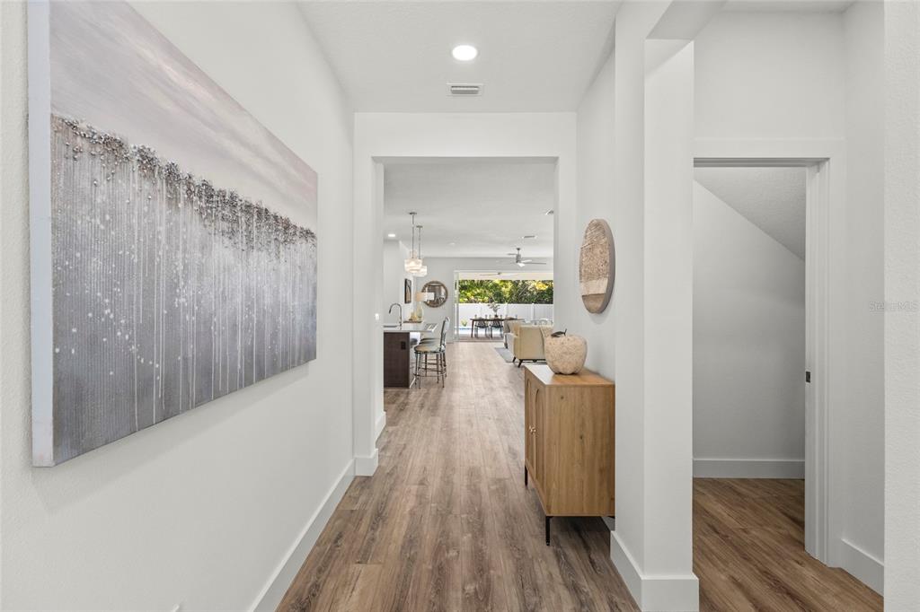 A bright hallway with wood-look flooring leads to an open-concept kitchen and living area — 217 S SHADE AVENUE, SARASOTA, FL