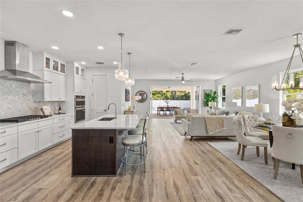 An open-concept kitchen and living area features white cabinetry, a dark island, and wood flooring — 217 S SHADE AVENUE, SARASOTA, FL