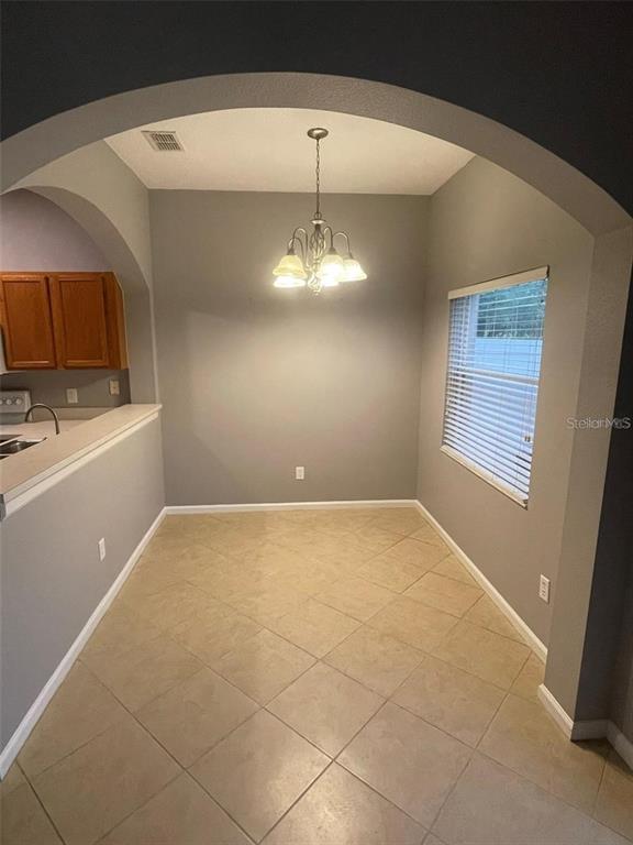 A dining area features tile flooring, gray walls, an arched entryway, and a hanging chandelier — 16265 OLD ASH LOOP, ORLANDO, FL