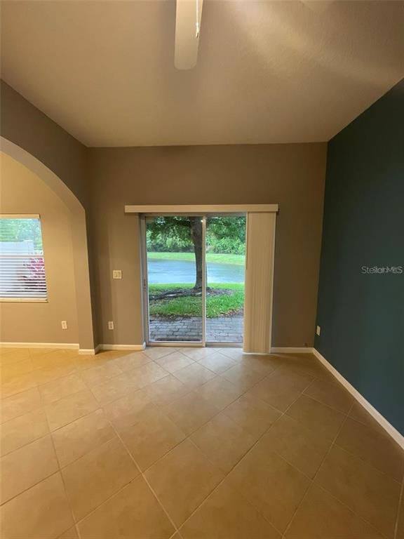 A room with tile flooring, a dark accent wall, and sliding glass doors to a pond — 16265 OLD ASH LOOP, ORLANDO, FL