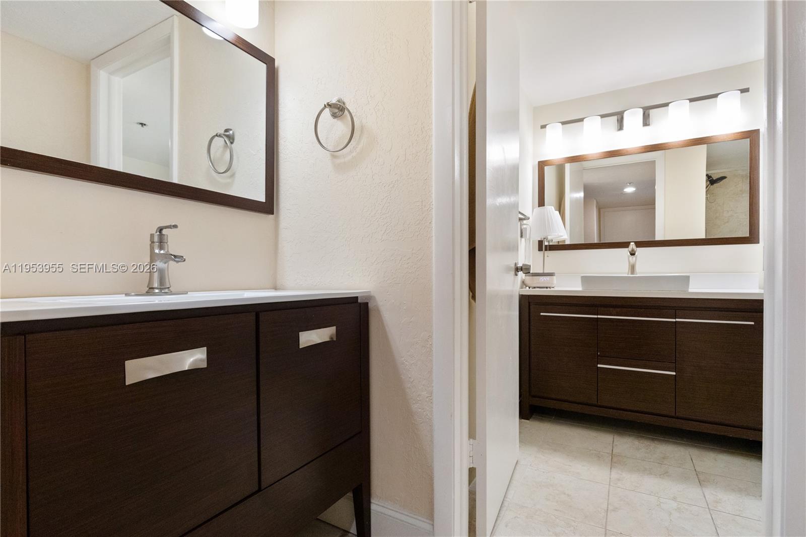 Two bathrooms feature dark wood vanities, white countertops, and rectangular mirrors — 300 Three Islands Blvd # 417, Hallandale Beach FL 33009, HALLANDALE BEACH, FL