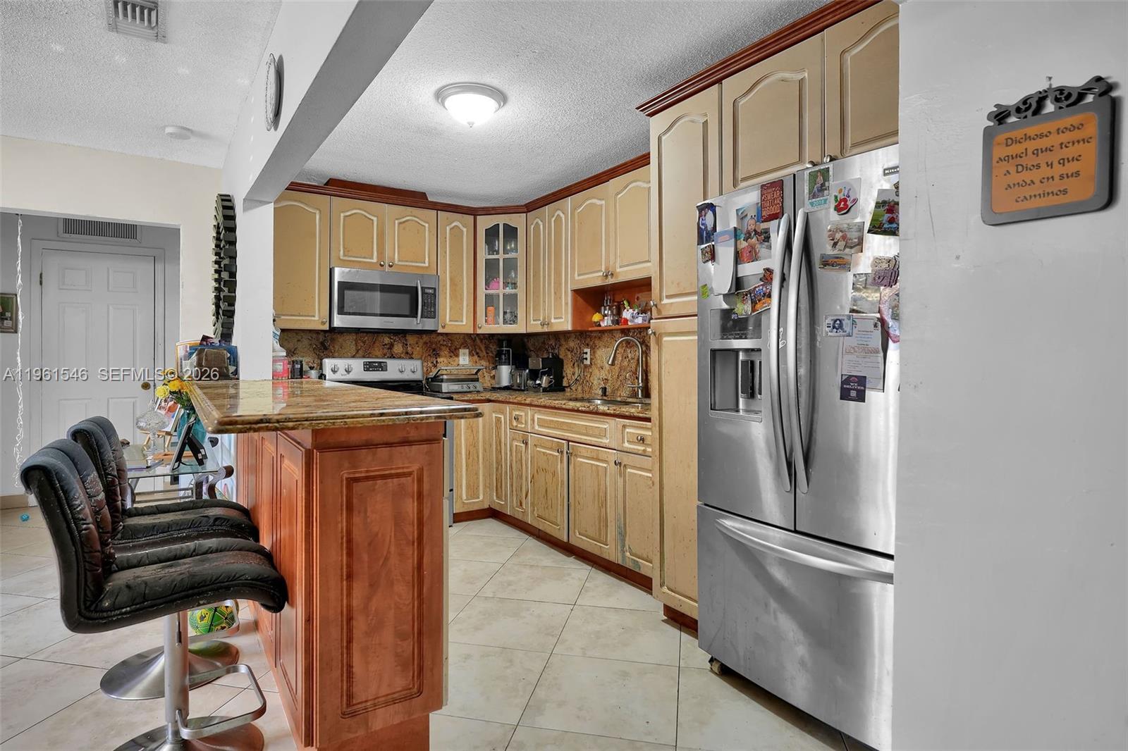 A kitchen features light-colored wooden cabinets, granite countertops, stainless steel appliances, and a breakfast bar — 2821 SW 65th Ave, Miami FL 33155, MIAMI, FL