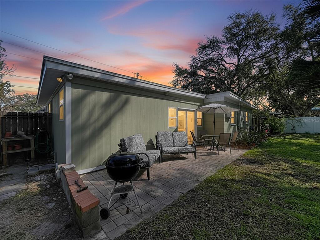A backyard patio features a brick paver floor, outdoor furniture, and a charcoal grill — 4042 ARKANSAS AVENUE NE, ST PETERSBURG, FL