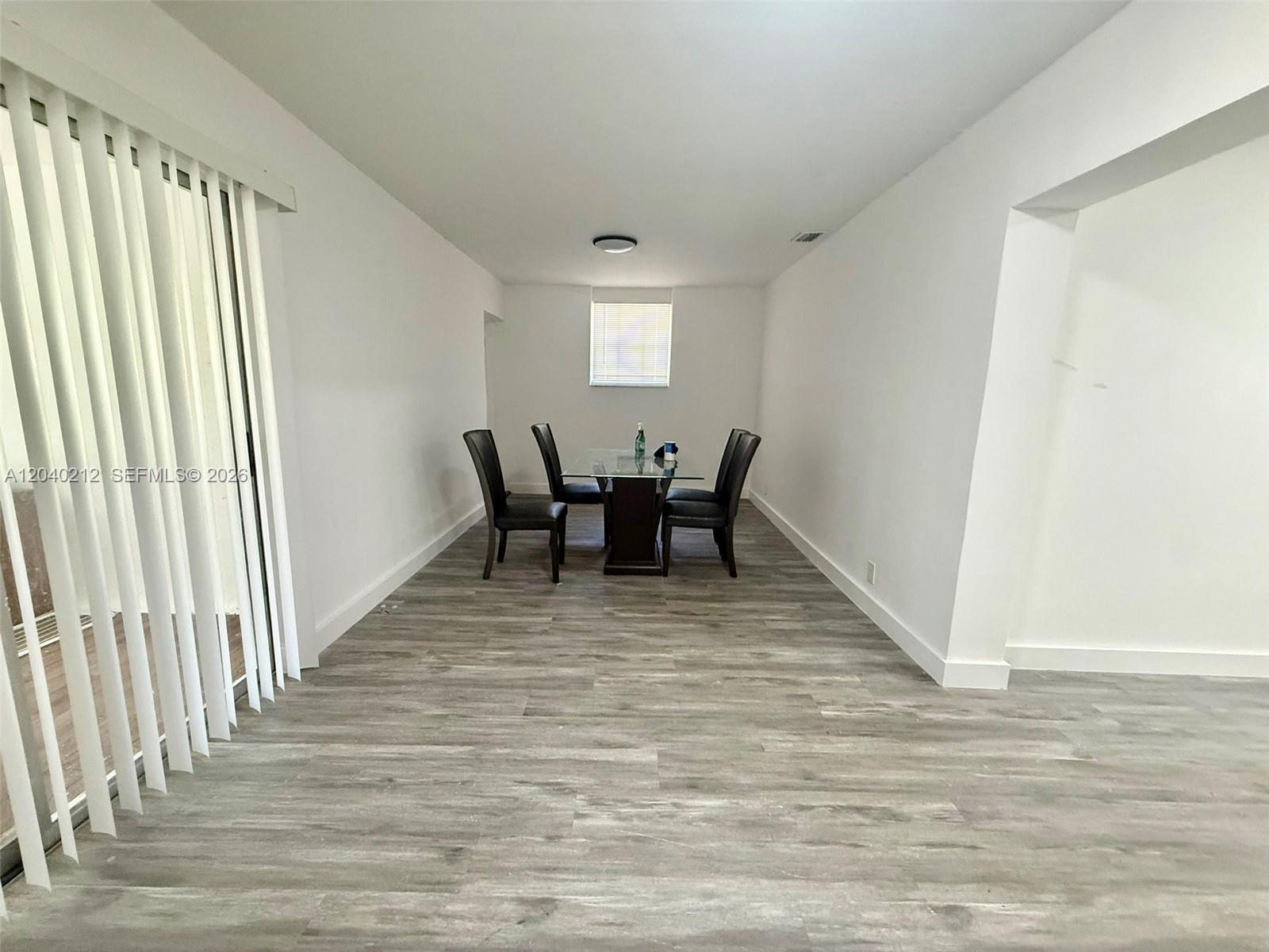 A dining room features gray wood-look flooring, white walls, and a glass-top table with chairs — 730 SW 5th St # 1, Hallandale Beach FL 33009, HALLANDALE BEACH, FL