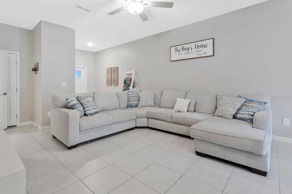 A living room features a large gray sectional sofa on tile flooring under a ceiling fan — 6283 SHINER STREET, LAND O LAKES, FL