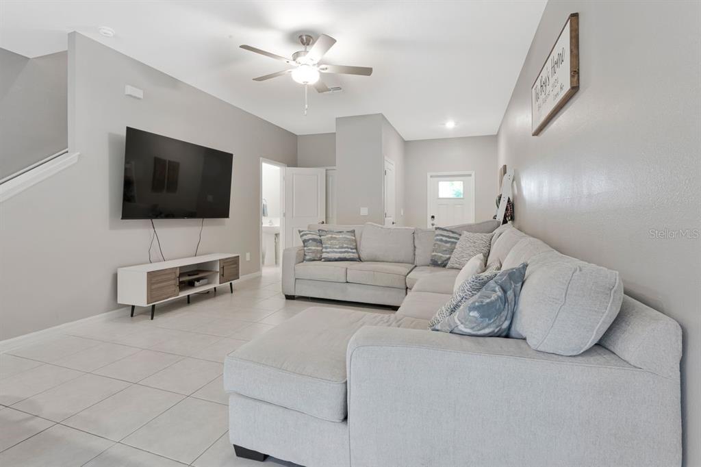 A living room features a large sectional sofa, a wall-mounted television, and tile flooring — 6283 SHINER STREET, LAND O LAKES, FL