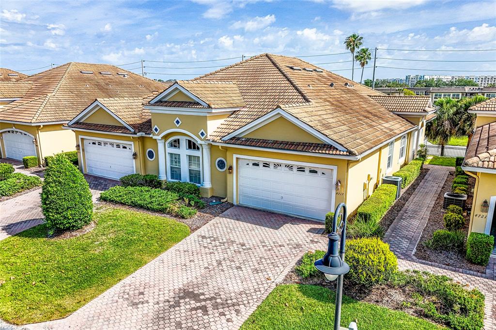 A yellow stucco house with a tiled roof, two garage doors, and a paved driveway — 4717 CASSWELL DRIVE, NEW PORT RICHEY, FL
