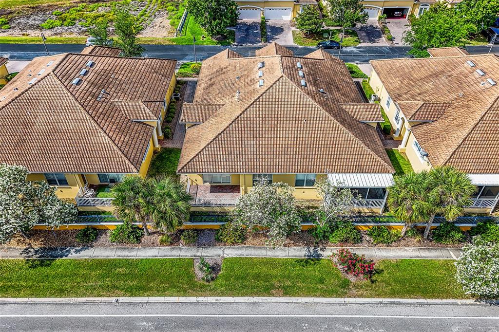 An aerial view shows three attached yellow houses with brown tile roofs and back patios — 4717 CASSWELL DRIVE, NEW PORT RICHEY, FL