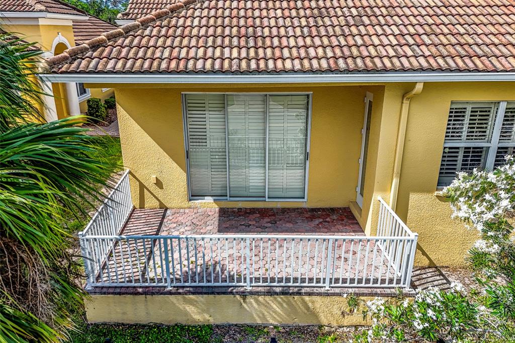 A yellow house exterior features a paved patio enclosed by a white metal railing — 4717 CASSWELL DRIVE, NEW PORT RICHEY, FL