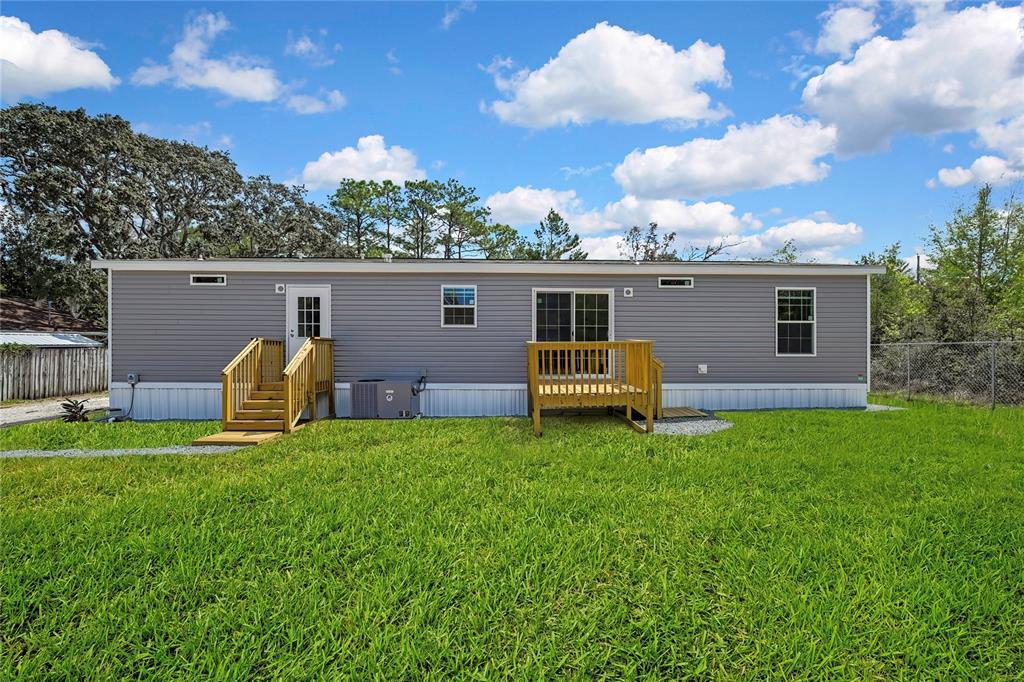 The exterior of a gray manufactured home features two wooden decks and a grassy yard — 5342 S ISABEL TERRACE, HOMOSASSA, FL